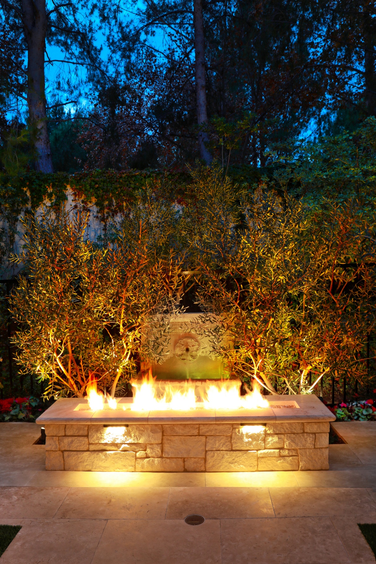 Stone fire pit in formal garden at night, Holmby Hills